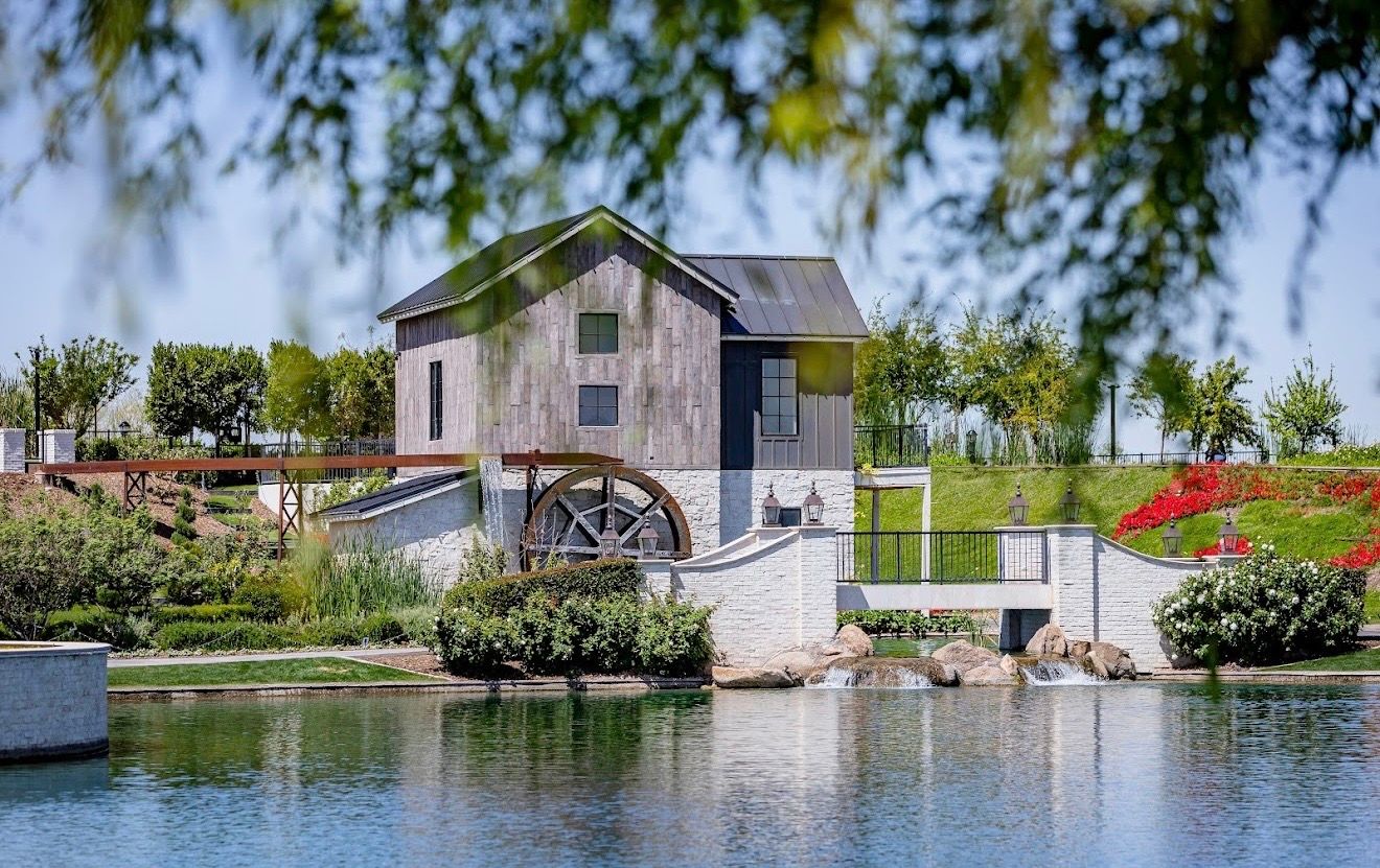 The gristmill and its waterwheel across the lake, framed by willow branches